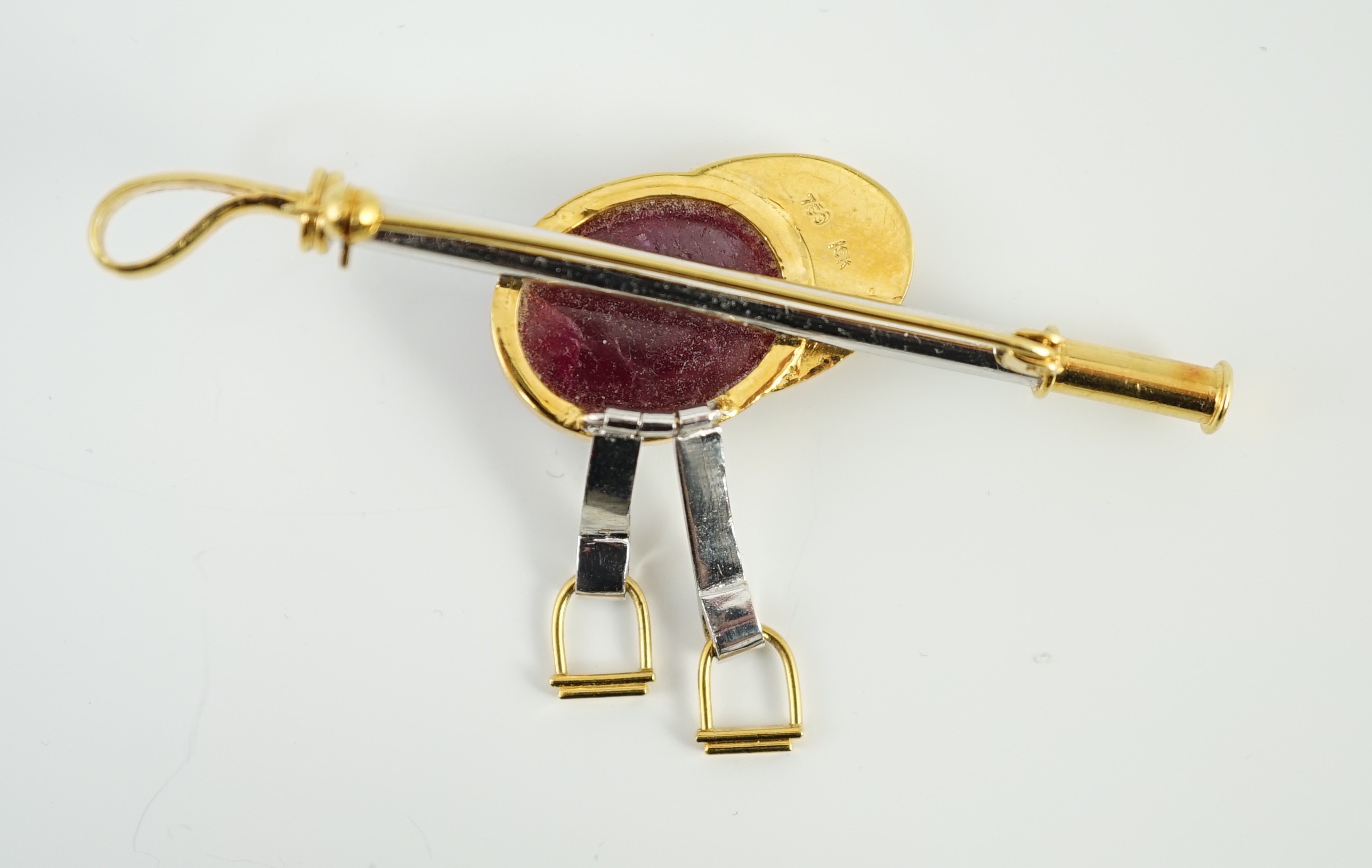 A late 20th century 18ct yellow and white gold, cabochon ruby set ‘jockey cap, riding crop and stirrups’ drop bar brooch